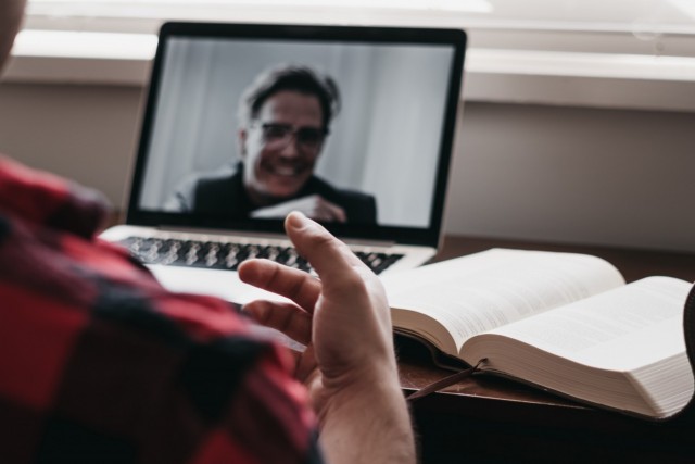 Talking via laptop with book